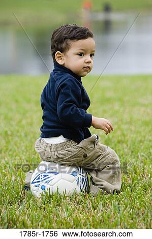 Stock Photograph - Boy sitting on a soccer ball. Fotosearch