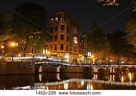Stock Photograph - Bridge with buildings lit up at night, Amsterdam, Netherlands. Fotosearch
