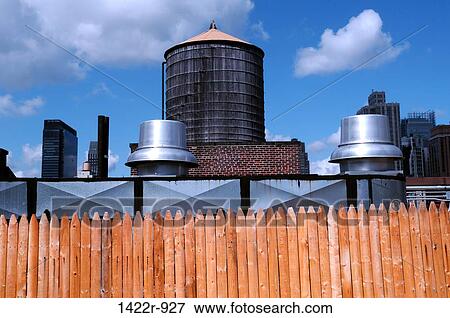 Stock Photo - Building rooftops against cloudy blue sky. Fotosearch