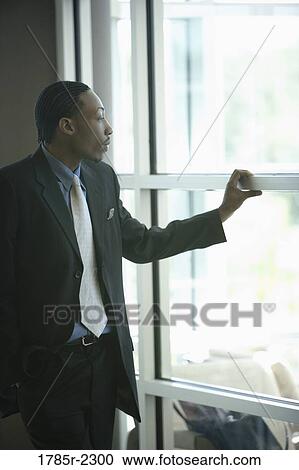 Businessman looking through window View Large Photo Image Stock Image - Businessman looking through window. Fotosearch