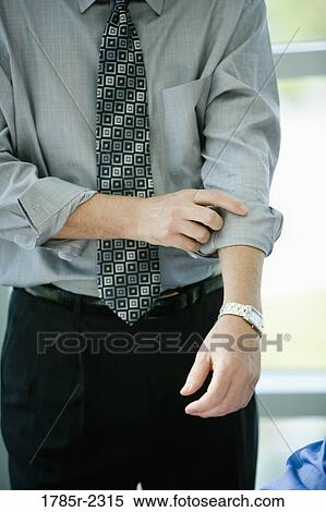 Businessman rolling up his sleeves View Large Photo Image Stock Photography - Businessman rolling up his sleeves. Fotosearch