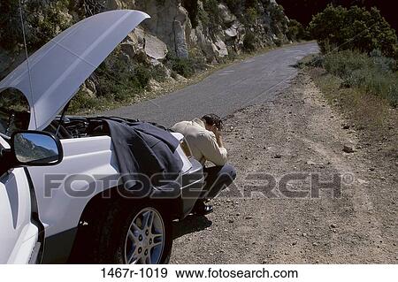 Businessman squatting in front of a broken down car View Large Photo Image Stock Photo - Businessman squatting in front of a broken down car. Fotosearch