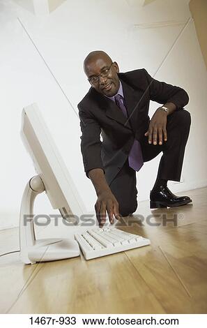 Businessman squatting on the floor looking at a computer monitor View Large Photo Image Stock Image - Businessman squatting on the floor looking at a computer monitor. Fotosearch