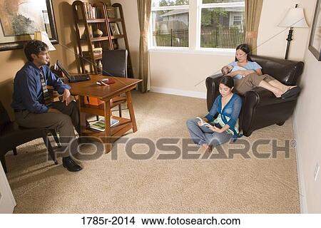 Businessman using laptop computer in the study of his home while conversing with his family View Large Photo Image Picture - Businessman using laptop computer in the study of his home while conversing with his family. Fotosearch