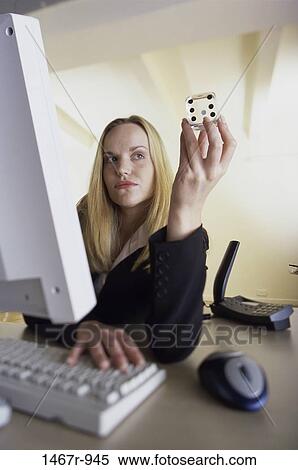 Businesswoman holding a dice while operating a computer View Large Photo Image Stock Photography - Businesswoman holding a dice while operating a computer. Fotosearch