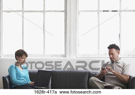 Businesswoman working on a laptop with a businessman using a PDA View Large Photo Image Stock Image - Businesswoman working on a laptop with a businessman using a PDA. Fotosearch
