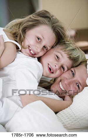 Cheek to cheek portrait of a mother with her young son and daughter View Large Photo Image Stock Photograph - Cheek to cheek portrait of a mother with her young son and daughter. Fotosearch