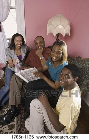 Cheerful family in living room looking at photo album View Large Photo Image Stock Photography - Cheerful family in living room looking at photo album. Fotosearch