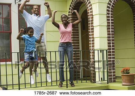 Cheerful family jumping outside a house View Large Photo Image Stock Photo - Cheerful family jumping outside a house. Fotosearch