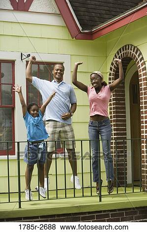 Cheerful family jumping outside a house View Large Photo Image Stock Photo - Cheerful family jumping outside a house. Fotosearch