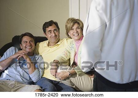Stock Image - Cheerful family sitting inside a house. Fotosearch