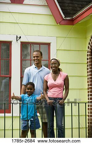 Cheerful family standing by a railing outside a house View Large Photo Image Picture - Cheerful family standing by a railing outside a house. Fotosearch