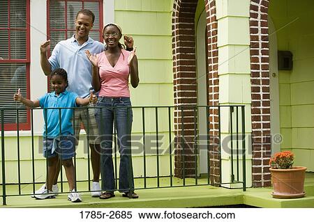 Cheerful family standing by a railing outside a house View Large Photo Image Stock Photography - Cheerful family standing by a railing outside a house. Fotosearch