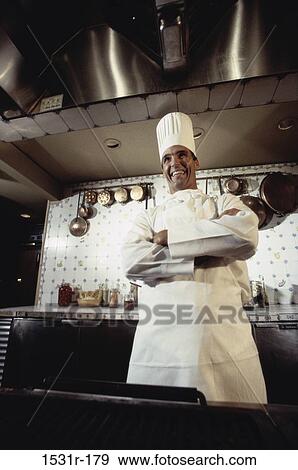 Stock Photo - Chef standing in a kitchen with his arms folded. Fotosearch