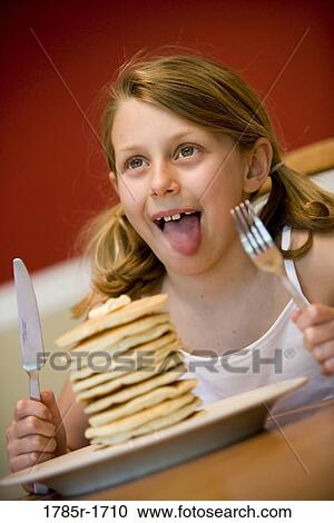 Stock Image - Child ready to eat huge stack of pancakes. Fotosearch