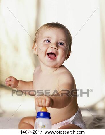 Stock Photo - Close-up of a baby boy holding a milk bottle. Fotosearch