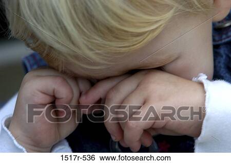 Stock Photograph - Close-up of a baby boy rubbing its eyes. Fotosearch