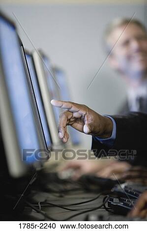 Stock Image - Close-up of a human hand pointing at computer screen. Fotosearch
