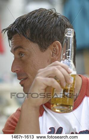 Close-up of a man holding a bottle of beer View Large Photo Image Stock Image - Close-up of a man holding a bottle of beer. Fotosearch