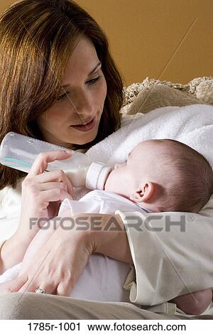 Stock Image - Close-up of a mother bottle-feeding baby. Fotosearch