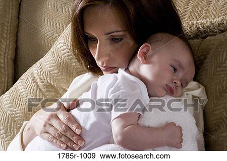 Stock Photo - Close-up of a mother holding a sleeping infant on her shoulders. Fotosearch