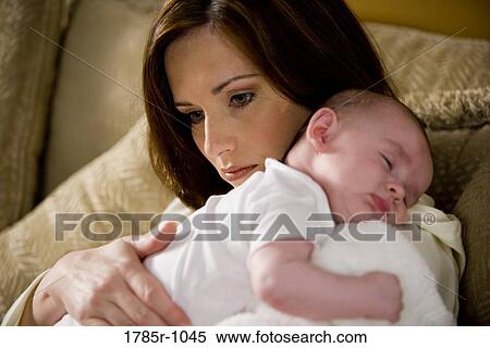 Stock Photography - Close-up of a mother holding a sleeping infant on her shoulders. Fotosearch