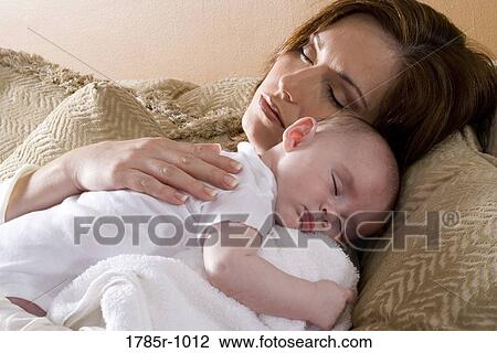 Stock Image - Close-up of a sleeping mother holding a sleeping infant on her shoulders. Fotosearch