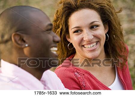 Stock Image - Close-up of a young multi-ethnic couple smiling. Fotosearch