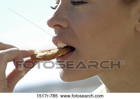 Close-up of a young woman eating a cookie View Large Photo Image Stock Photography - Close-up of a young woman eating a cookie. Fotosearch