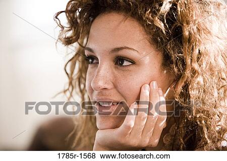 Stock Photo - Close-up of a young woman resting her chin on the palm of her hand. Fotosearch