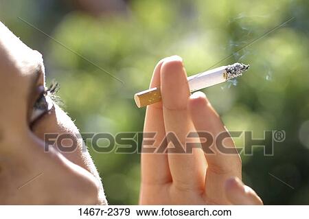 Close-up of a young woman smoking a cigarette View Large Photo Image Stock Photo - Close-up of a young woman smoking a cigarette. Fotosearch