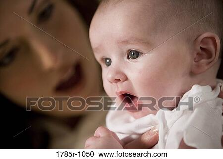 Stock Image - Close-up of an infant being held by his mother. Fotosearch