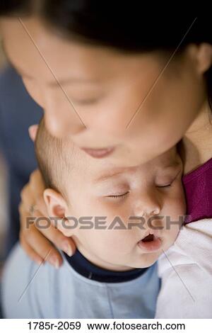 Close-up of an infant boy falling asleep while being held by his mother View Large Photo Image Stock Photo - Close-up of an infant boy falling asleep while being held by his mother. Fotosearch