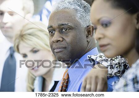 Close-up of business colleagues standing in a row, focus on man View Large Photo Image Stock Photography - Close-up of business colleagues standing in a row, focus on man. Fotosearch