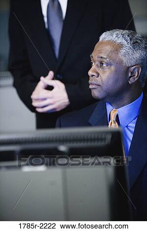 Stock Image - Close-up of businessmen in front of computer monitor. Fotosearch