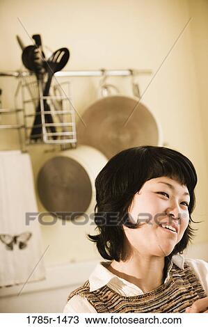 Close-up of young Asian woman smiling in kitchen View Large Photo Image Stock Image - Close-up of young Asian woman smiling in kitchen. Fotosearch