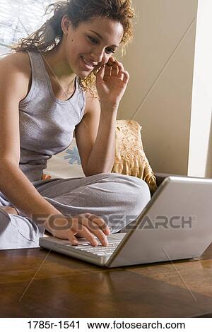 Close-up of young woman sitting on sofa using a laptop computer View Large Photo Image Stock Image - Close-up of young woman sitting on sofa using a laptop computer. Fotosearch