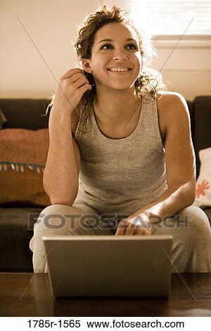Close-up of young woman sitting on sofa using a laptop computer View Large Photo Image Stock Photography - Close-up of young woman sitting on sofa using a laptop computer. Fotosearch