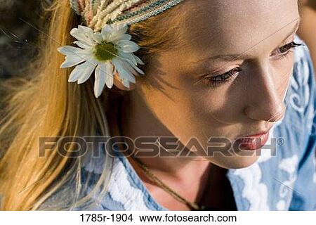 Picture - Close-up portrait of a young woman with a flower in her hair. Fotosearch