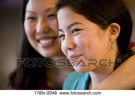 Close-up portrait of an Asian mother embracing her Asian-Caucasian daughter in the kitchen View Large Photo Image Stock Photo - Close-up portrait of an Asian mother embracing her Asian-Caucasian daughter in the kitchen. Fotosearch