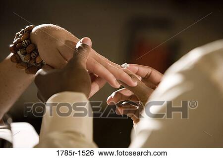 Close-up view of a man's hands putting diamond ring on woman's finger View Large Photo Image Stock Photograph - Close-up view of a man's hands putting diamond ring on woman's finger. Fotosearch