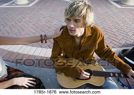 Close-up view of a young man in vintage 1960's costumes with a guitar View Large Photo Image Stock Photograph - Close-up view of a young man in vintage 1960's costumes with a guitar. Fotosearch