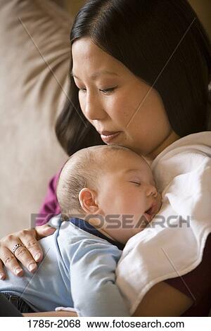 Close-up view of an infant boy falling asleep while being held by his mother View Large Photo Image Stock Photo - Close-up view of an infant boy falling asleep while being held by his mother. Fotosearch