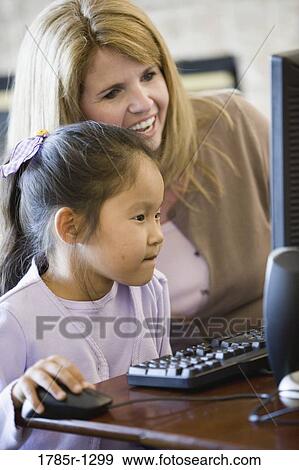 Daughter and mother looking at a computer View Large Photo Image Stock Photo - Daughter and mother looking at a computer. Fotosearch