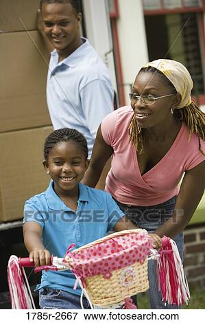 Daughter riding a bicycle while dad unloads moving truck View Large Photo Image Stock Photo - Daughter riding a bicycle while dad unloads moving truck. Fotosearch