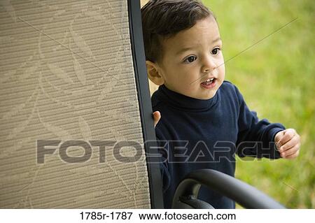 Elevated view of a little boy standing by a chair View Large Photo Image Stock Photo - Elevated view of a little boy standing by a chair. Fotosearch