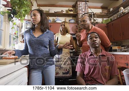 Family conversing in kitchen while son listens to headphones View Large Photo Image Picture - Family conversing in kitchen while son listens to headphones. Fotosearch