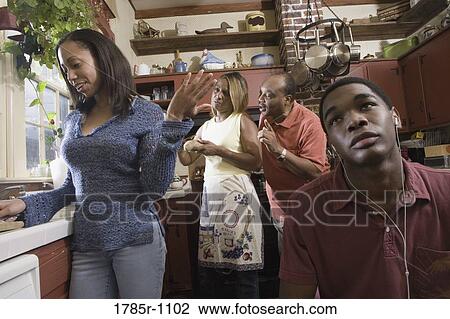 Family conversing in kitchen while son listens to headphones View Large Photo Image Stock Image - Family conversing in kitchen while son listens to headphones. Fotosearch