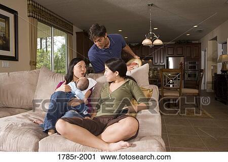 Stock Image - Family in living room on sofa. Fotosearch