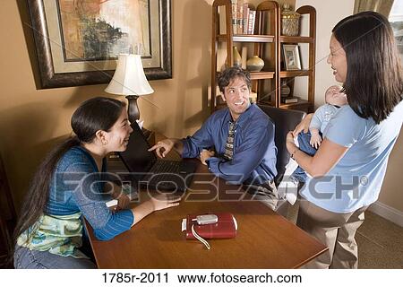 Stock Image - Family looking at laptop computer at home. Fotosearch